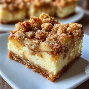 Delicious apple streusel cheesecake bars topped with crumble and sliced apples.