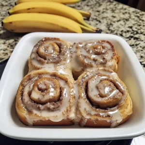Freshly baked banana bread cinnamon rolls topped with creamy icing.