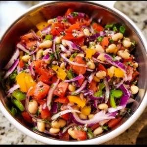 Colorful dense bean salad with mixed beans, vegetables, and dressing in a bowl.