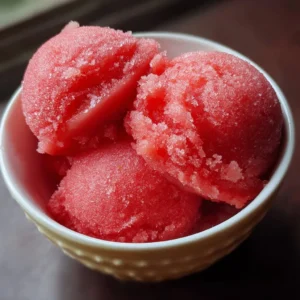Homemade strawberry sorbet in a bowl with fresh strawberries