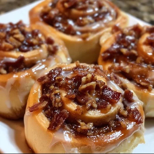 Bourbon Maple Bacon Cinnamon Rolls topped with a luscious glaze and crispy bacon.