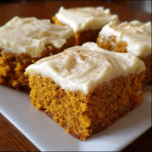 Delicious pumpkin bars with cream cheese frosting on a wooden table