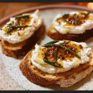 Whipped feta crostini drizzled with hot honey, served as an elegant appetizer.