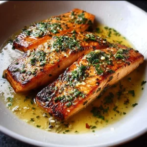 Pan fried salmon fillets drizzled with garlic butter sauce on a plate