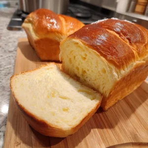 Freshly baked soft milk bread loaf on a wooden cutting board.