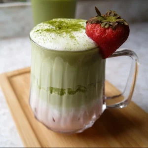 Iced Strawberry Matcha Latte in a clear glass with fresh strawberries and matcha powder