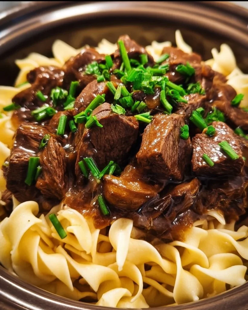 Crockpot beef tips served with noodles in a cozy bowl.