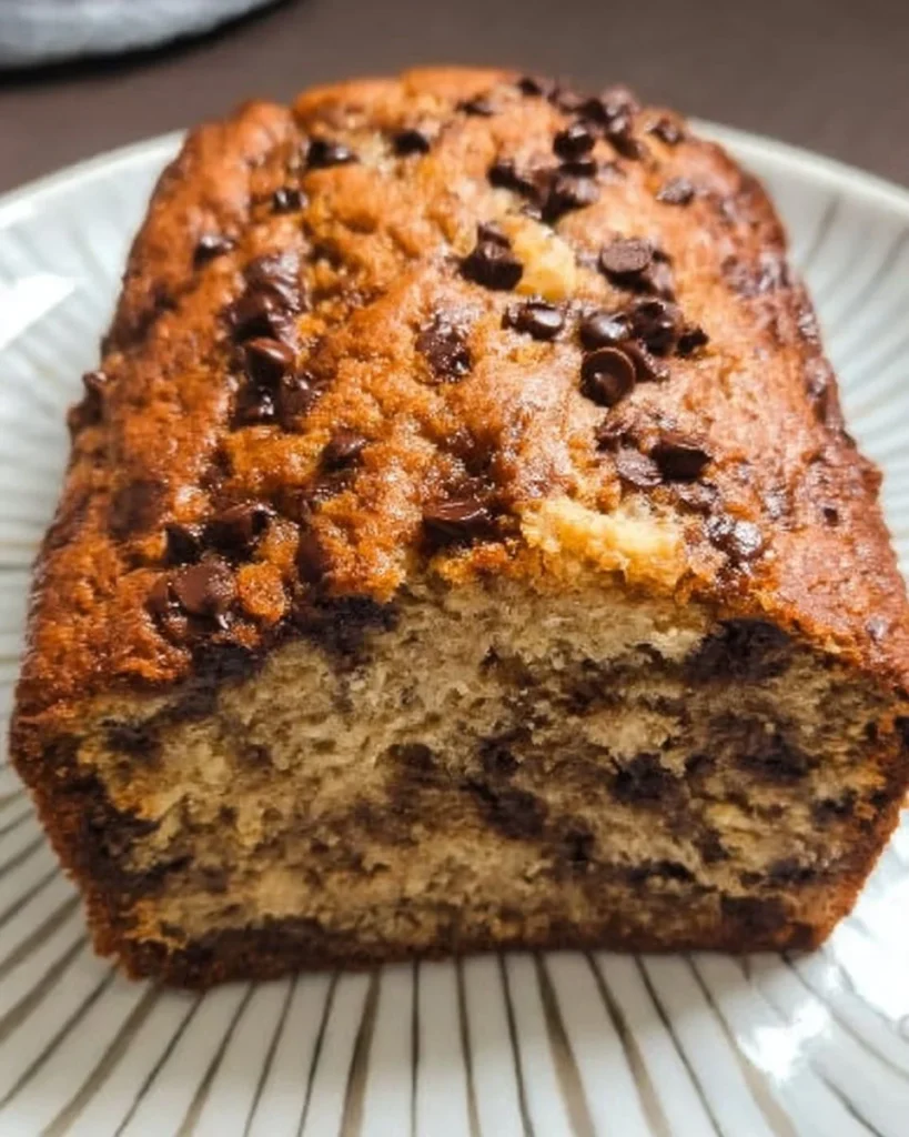 Slice of chocolate chip banana bread with chocolate chips on a plate