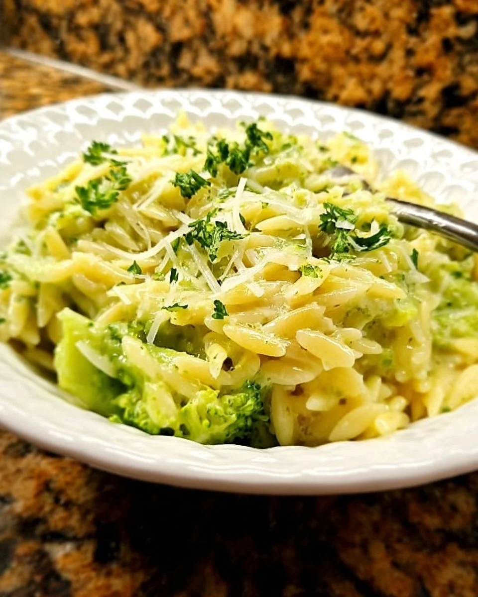Creamy broccoli orzo dish served in a bowl with fresh broccoli garnish.