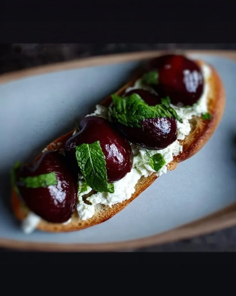 Roasted Cherry Crostini with feta cheese and fresh mint on a platter