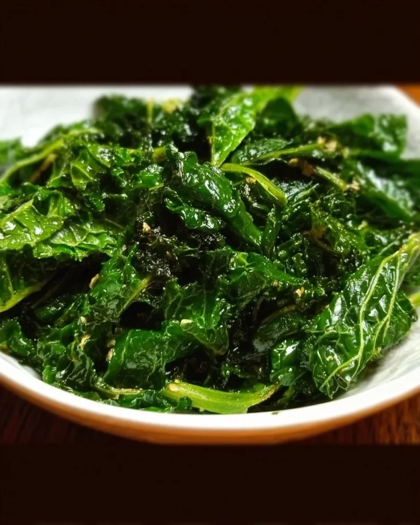 Plate of sautéed kale with garlic and olive oil, garnished with lemon.