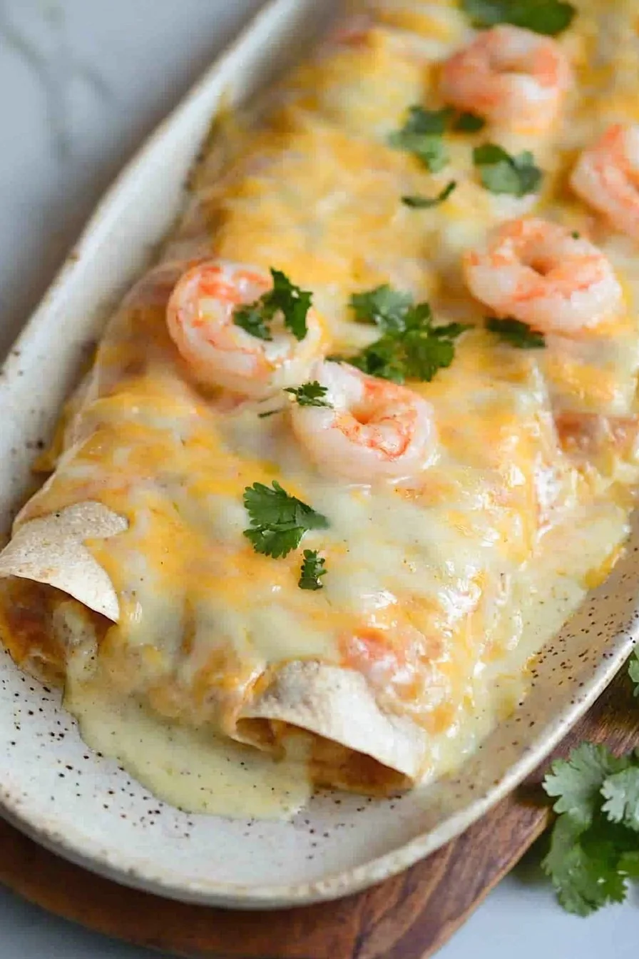 Creamy shrimp enchiladas topped with sauce and cheese