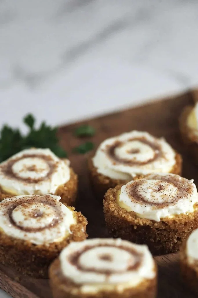 Mini cinnamon roll cheesecakes topped with cream cheese frosting and cinnamon.