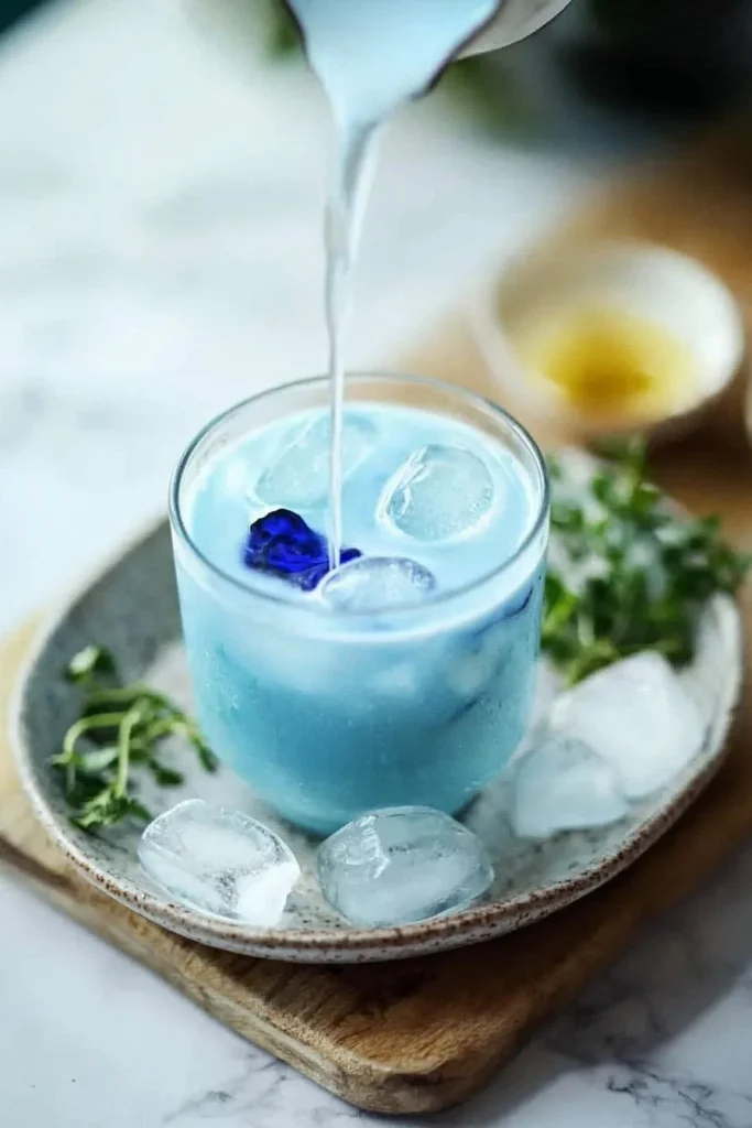 Glass of blue milk tea served with colorful sprinkles and a straw