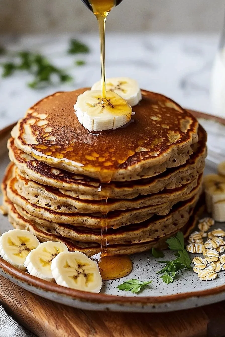 Healthy banana oatmeal pancakes stacked on a plate topped with fresh fruit