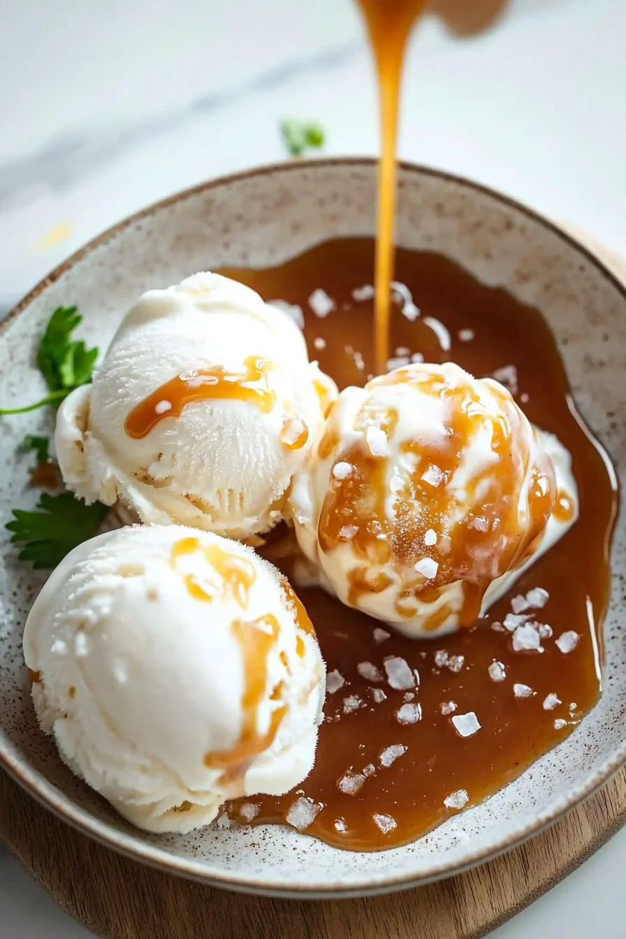 Bowl of homemade salted caramel ice cream topped with caramel drizzle and sea salt.