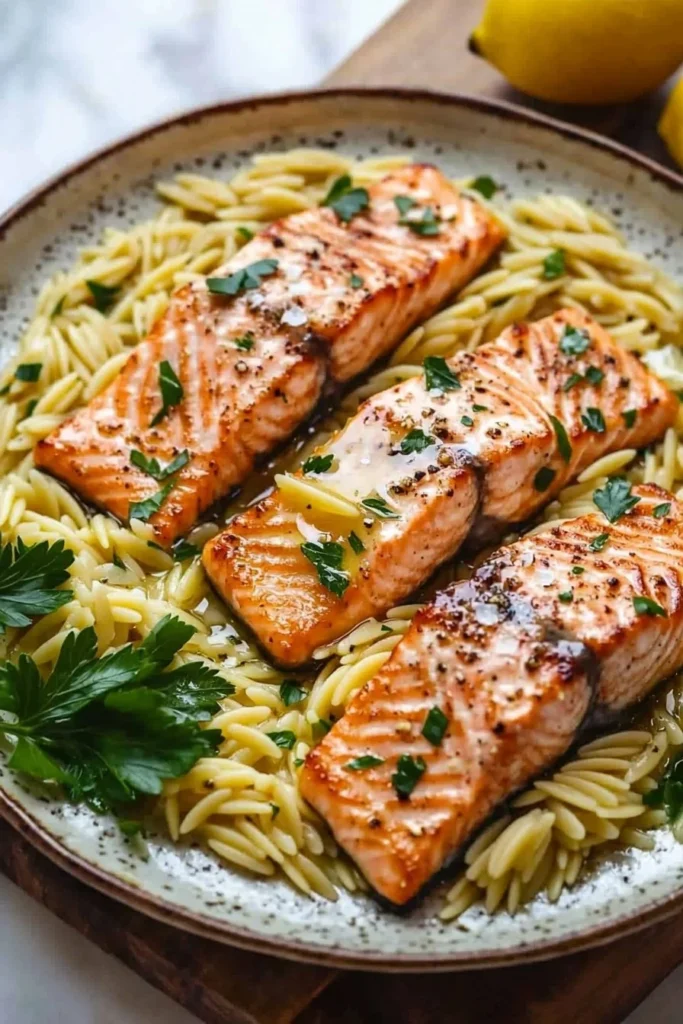 Plate of seared salmon served with lemon orzo and fresh herbs