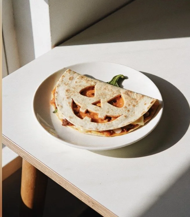 Halloween-themed Jack-O'-Lantern quesadillas with cheese and vibrant fillings.
