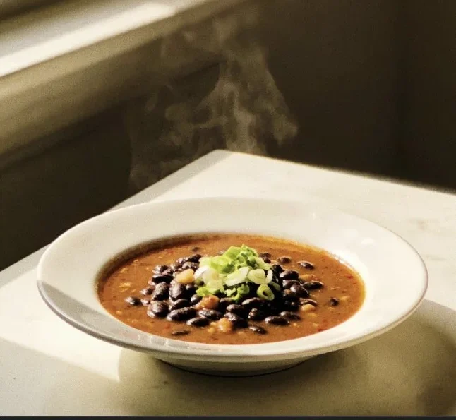 Bowl of spicy black bean soup garnished with cilantro and lime.